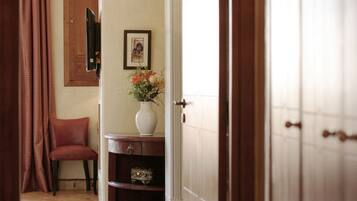 Un pasillo con una silla, un florero con flores, un cuadro en la pared y una puerta de madera.