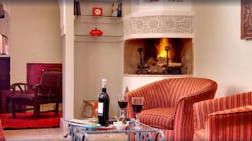 Un salón acogedor con chimenea, sillones a rayas, una mesita de centro y una estantería.
