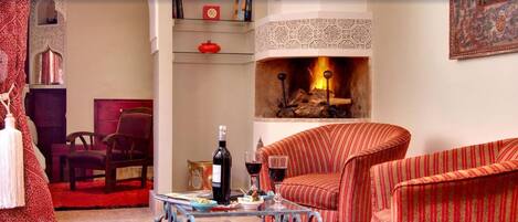 A cozy living room with a fireplace, striped armchairs, a coffee table, and a bookshelf.