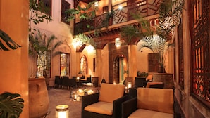 A cozy indoor seating area with wicker furniture, a large potted plant, and decorative lighting. - La Maison Arabe Hotel, Spa and Cooking Workshops (Marrakech)