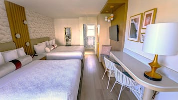 Habitación de hotel con dos camas, un escritorio con sillas, un espejo y un televisor en la pared.