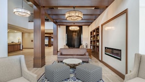 Un hall d’entrée spacieux avec un grand canapé, deux poufs à motifs, une table basse et une cheminée.