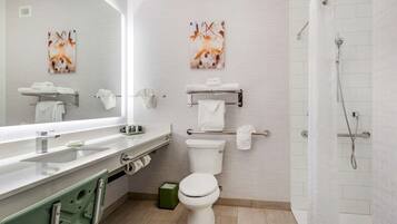 Un baño moderno con inodoro, lavabo y ducha. Hay toallas y un cubo de basura.