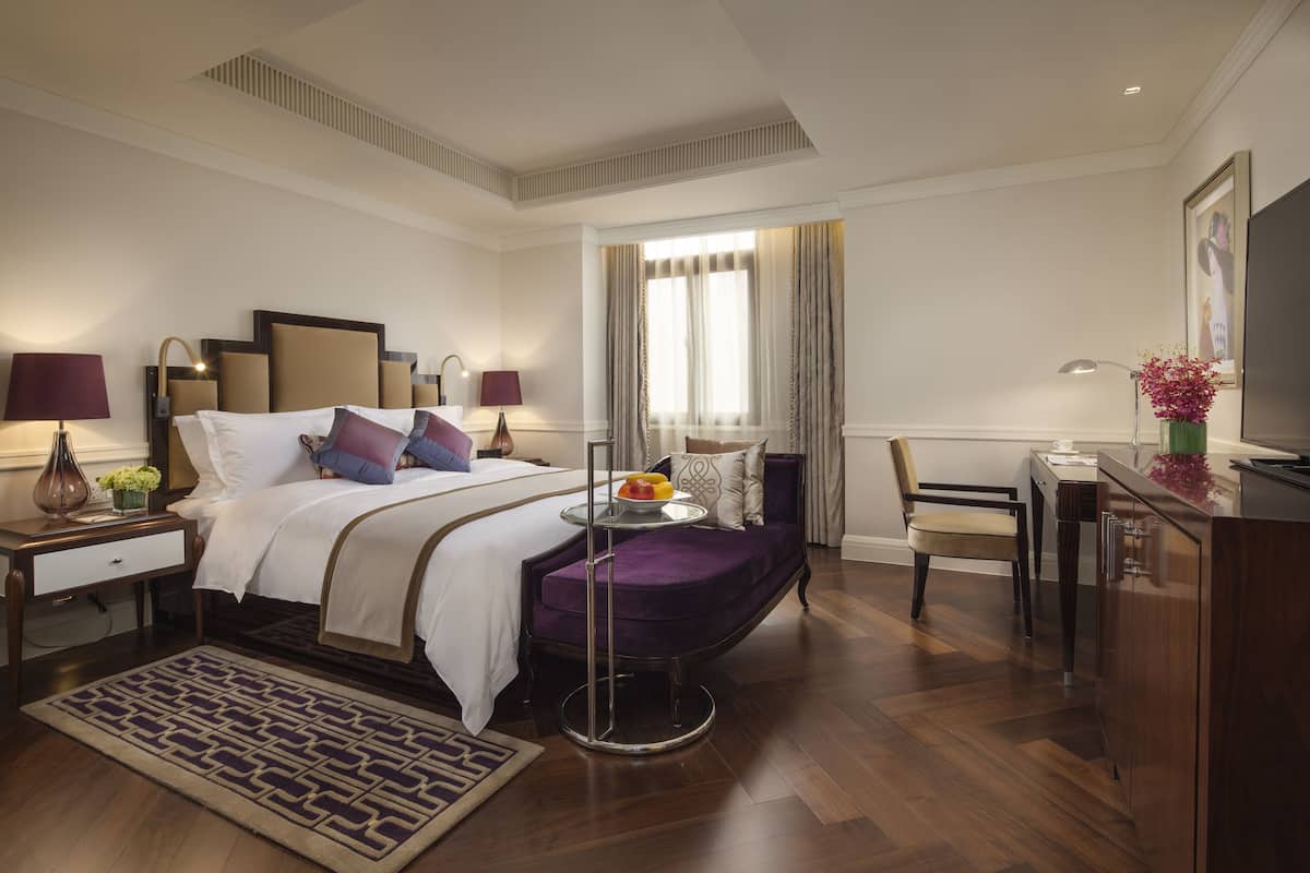 A hotel room with a bed, bedside tables, a desk, and a chair.