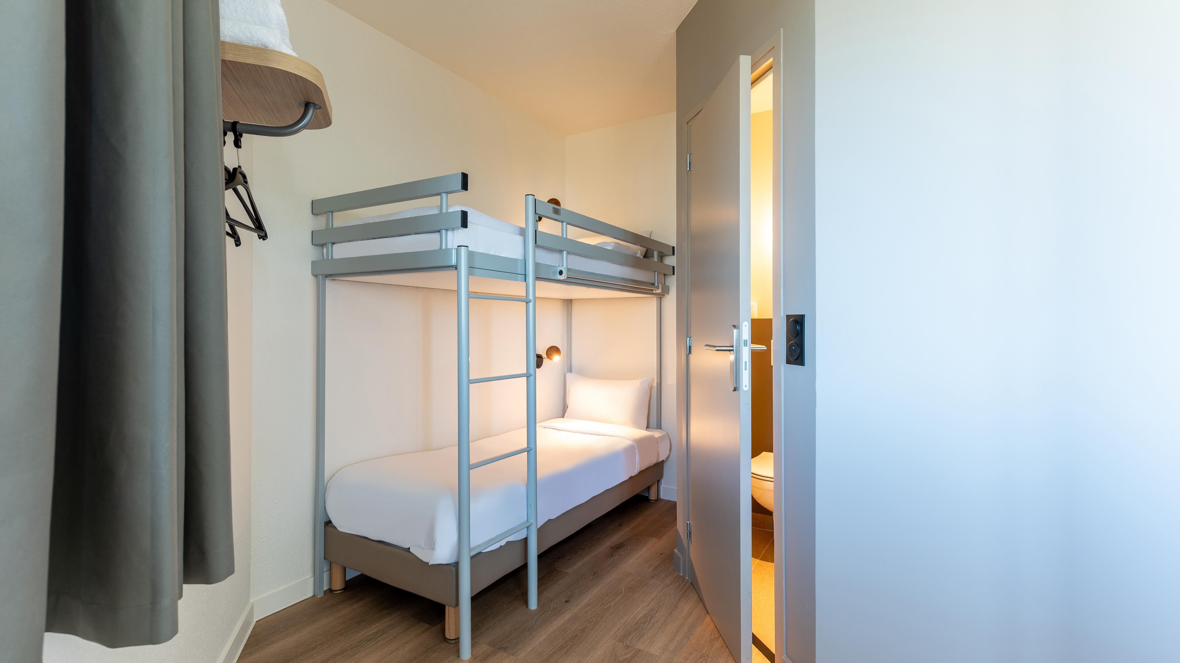 Habitación con literas y una puerta que da al baño.