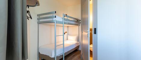 A bunk bed room with a door leading to a bathroom.