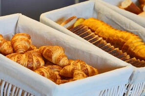 A display of assorted baked goods, including croissants and sliced bread, arranged in white baskets. - Kyriad ECO - Marne-la-Vallée Bussy-Saint-Georges (Bussy-Saint-Georges)