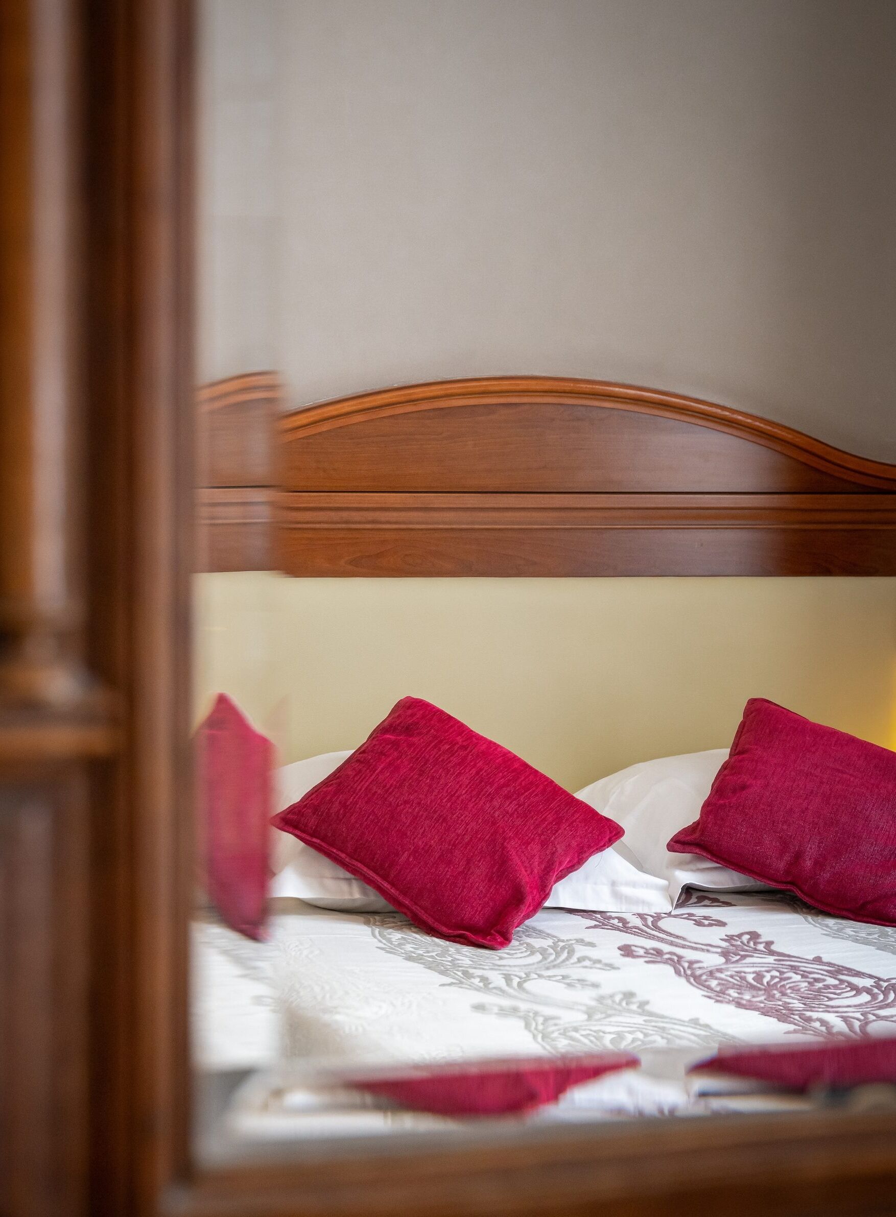 Una cama con cabecera de madera y dos almohadas rojas.