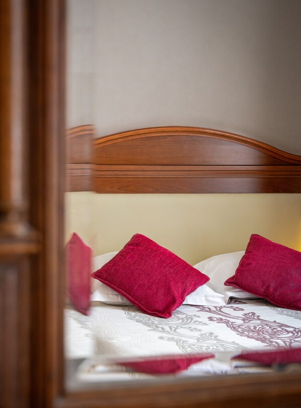 A bed with a wooden headboard and two red pillows. - Logis Hotel Central Montargis (Montargis)