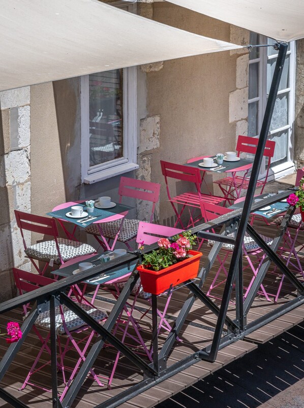 An outdoor café with tables and chairs, a window, and a planter with flowers. - Logis Hotel Central Montargis (Montargis)