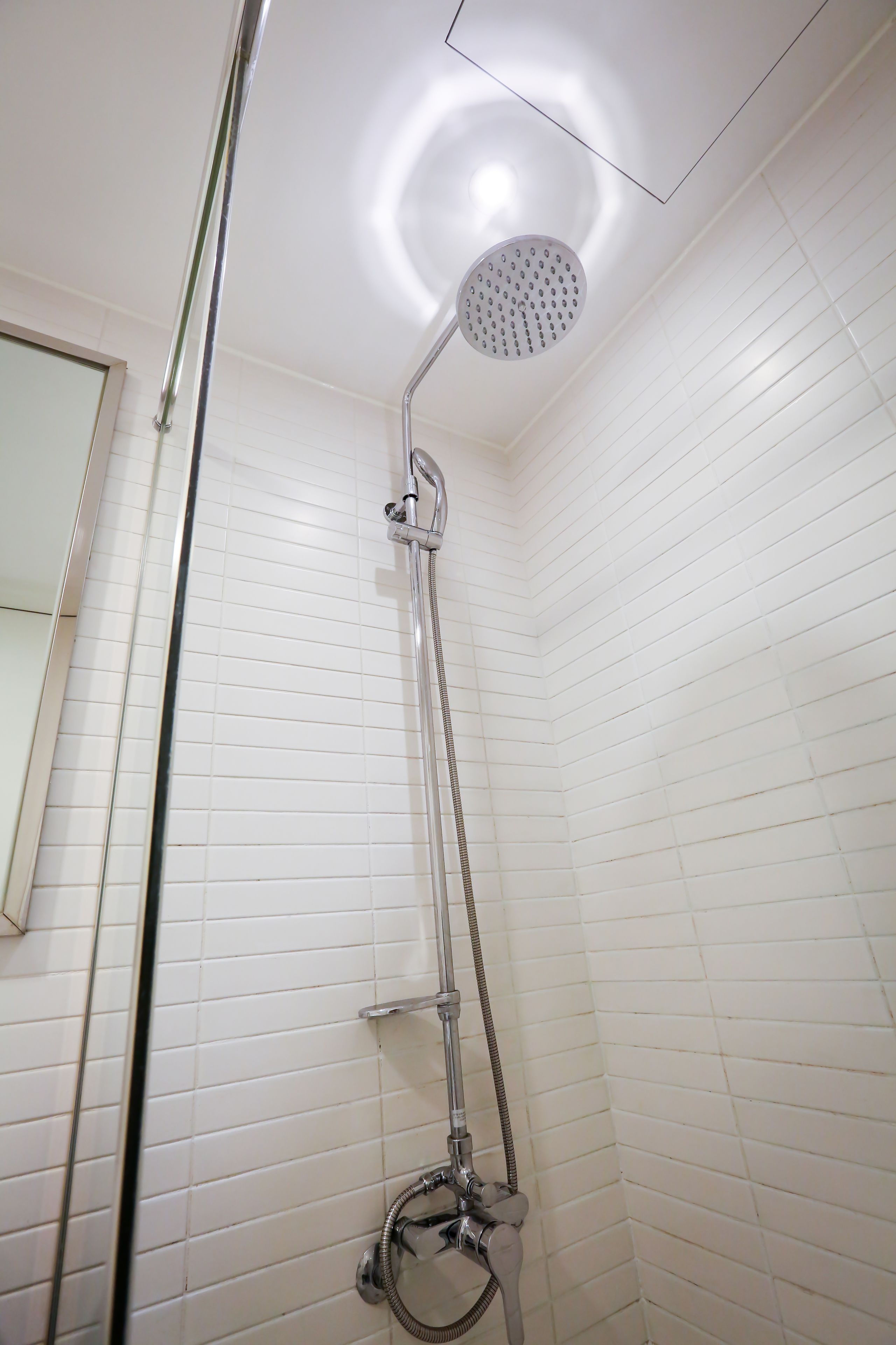 A shower with a handheld showerhead and a wall-mounted faucet.