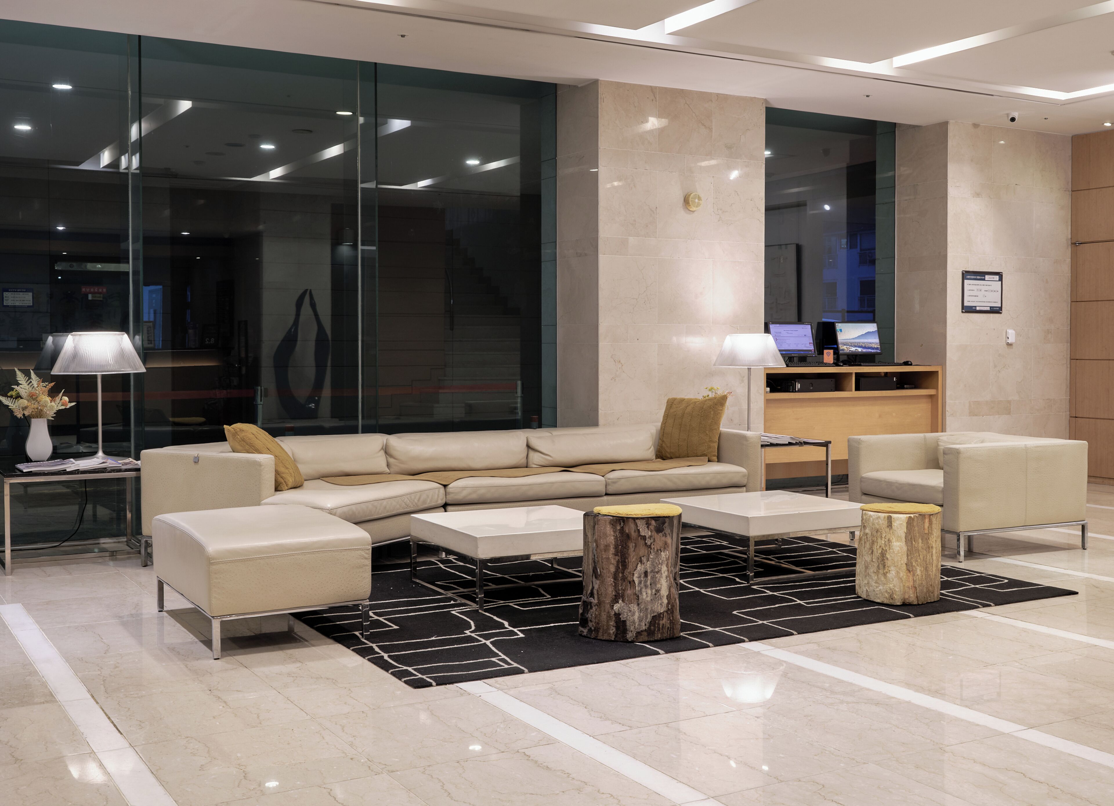 A modern lobby with a sectional sofa, a round coffee table, and a small side table with a lamp.
