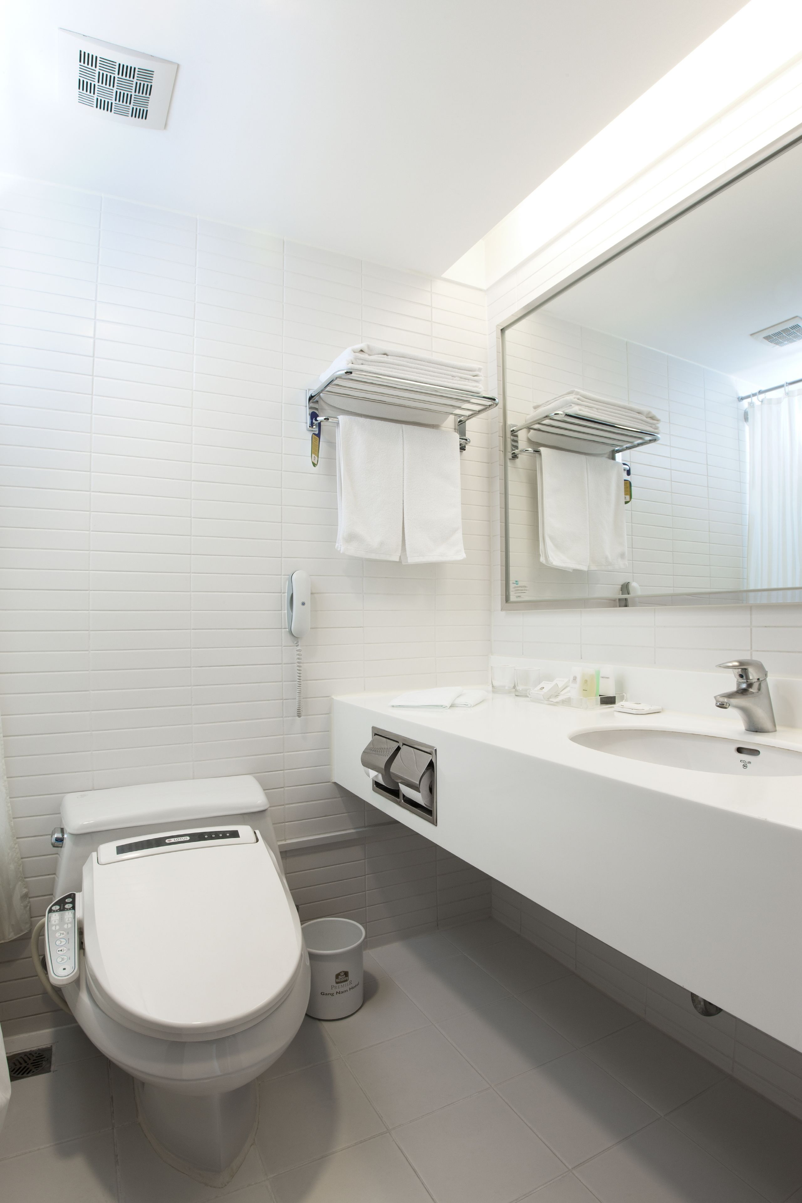 Une salle de bain moderne avec des toilettes blanches, un lavabo et un miroir.