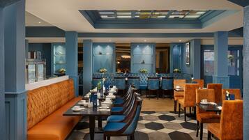 A restaurant with a long counter, blue upholstered booths, and a checkered floor.