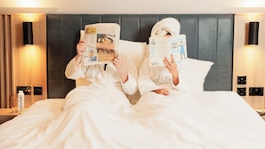 Two people reading books in a hotel room with a bed, bedside tables, and wall-mounted lamps. - Springfield Hotel (Leixlip)