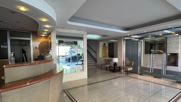 Vestíbulo de hotel con mostrador de recepción, zona de estar y una escalera que lleva a los pisos superiores.