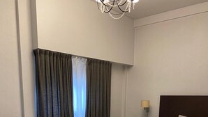 Una habitación de hotel moderna con cama, sofá, mesa de centro y mesita de noche con lámpara.