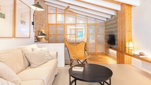 A modern living room with a sofa, a round table, a chair, and a TV. - Agroturismo sa Rota den Palerm (Lloret de Vistalegre)