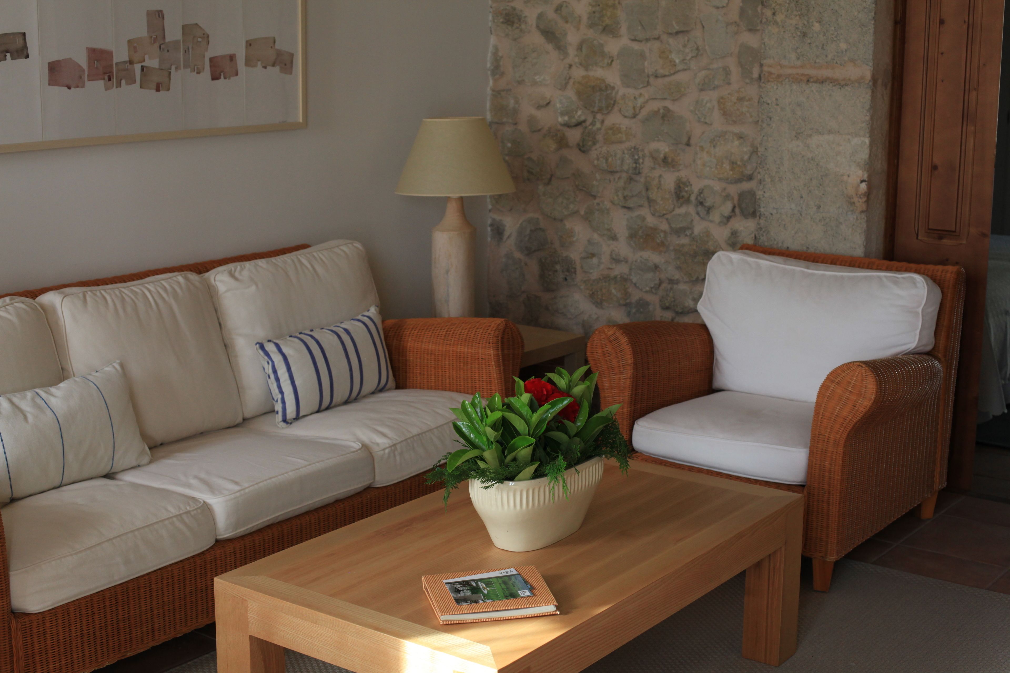 A living room with a sofa, a chair, a coffee table, a lamp, and a stone wall.