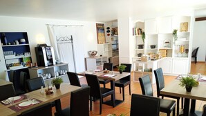A dining area with multiple tables and chairs, a coffee machine, and shelves with various items. - Le Mas des Amandiers (Graveson)