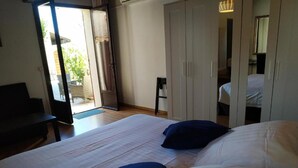 A bedroom with a large bed, a wardrobe, and a sliding glass door leading to a balcony. - Le Mas des Amandiers (Graveson)