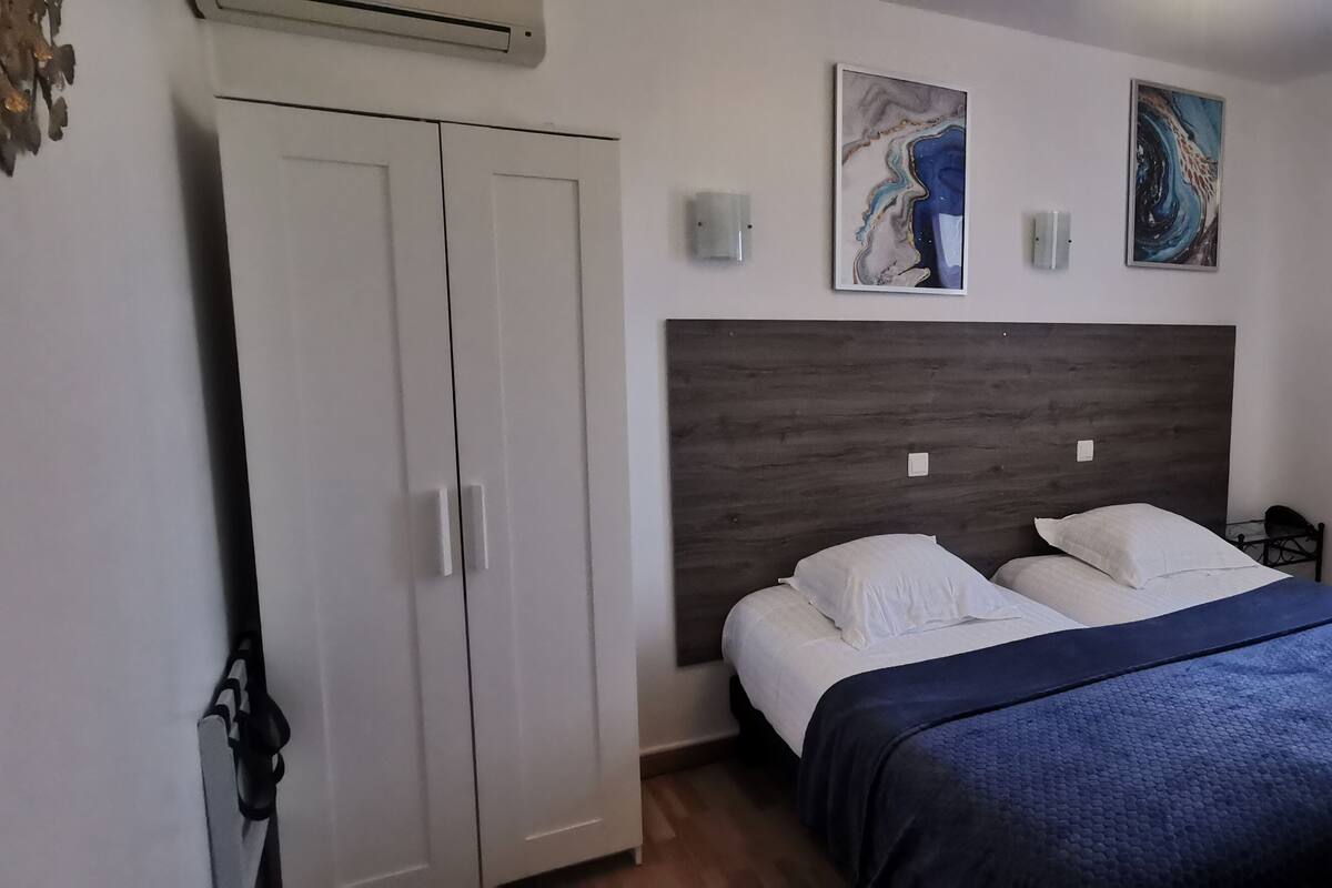 A bedroom with a bed, a wardrobe, and two wall-mounted light fixtures.