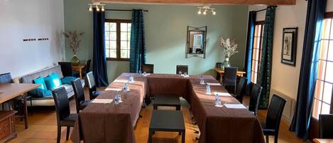 A conference room with a long table, chairs, and a small table with a vase of flowers.