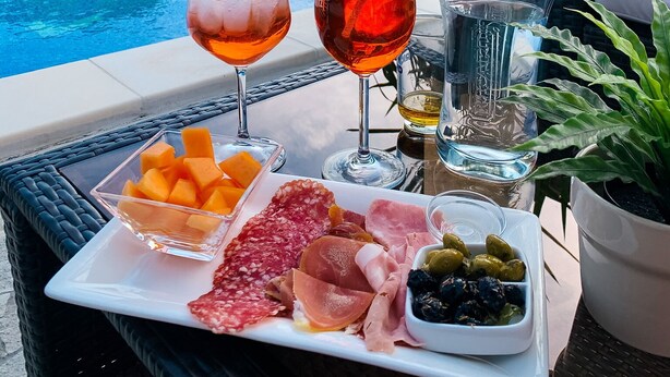 A poolside table with drinks, fruit, and charcuterie. - Le Mas des Amandiers (Graveson)