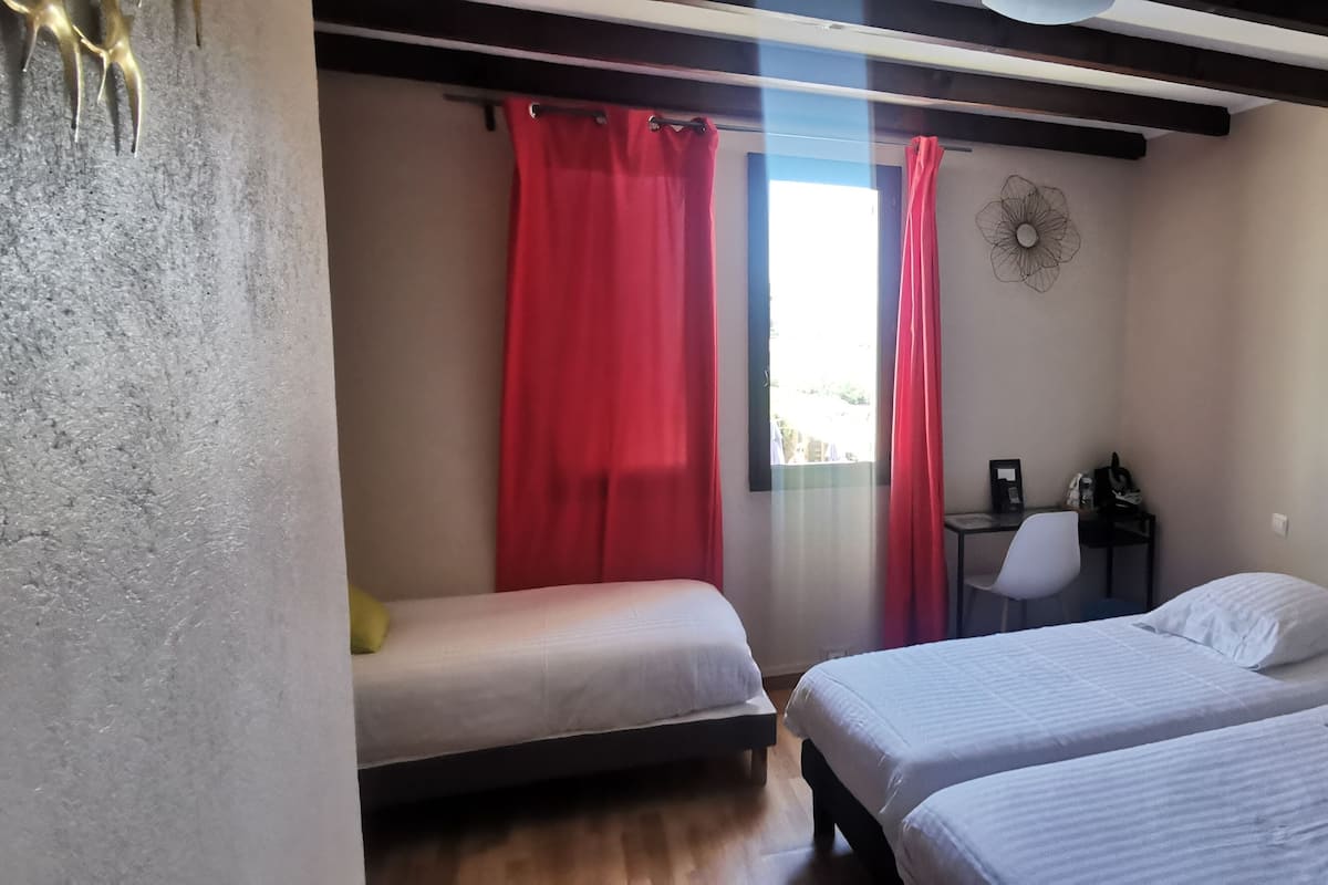 A room with two beds, a desk, and a chair.