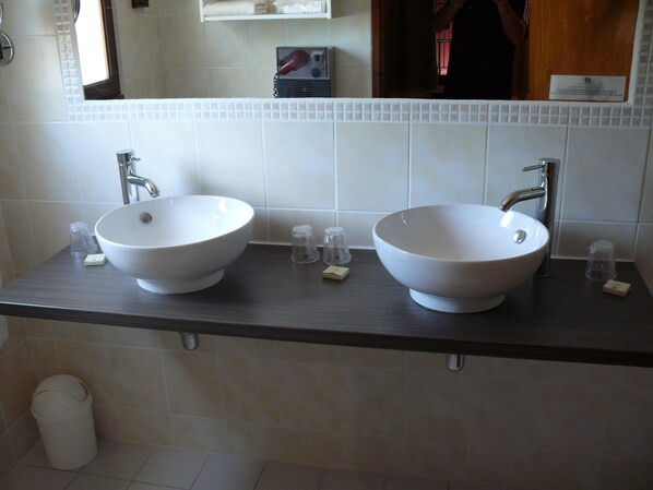 Un baño con dos lavamanos blancos, un espejo y un perchero para toallas.