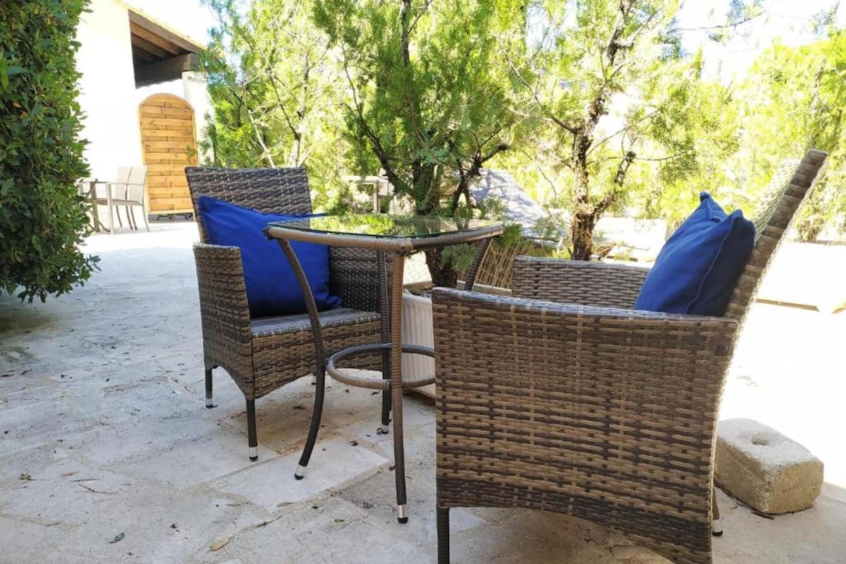 A patio area with wicker furniture and a stone floor.