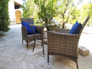 Un patio con mobiliario de mimbre y suelo de piedra.