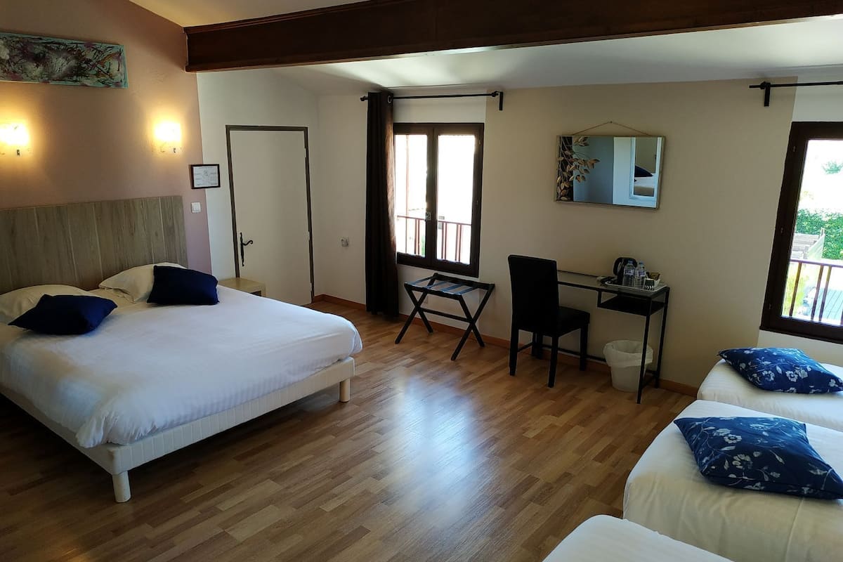 A hotel room with a bed, desk, chair, and a balcony view.