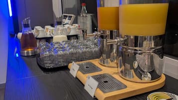 Zona de bar con dos grandes dispensadores de zumo, una selección de vasos y un atril con etiquetas de los productos.