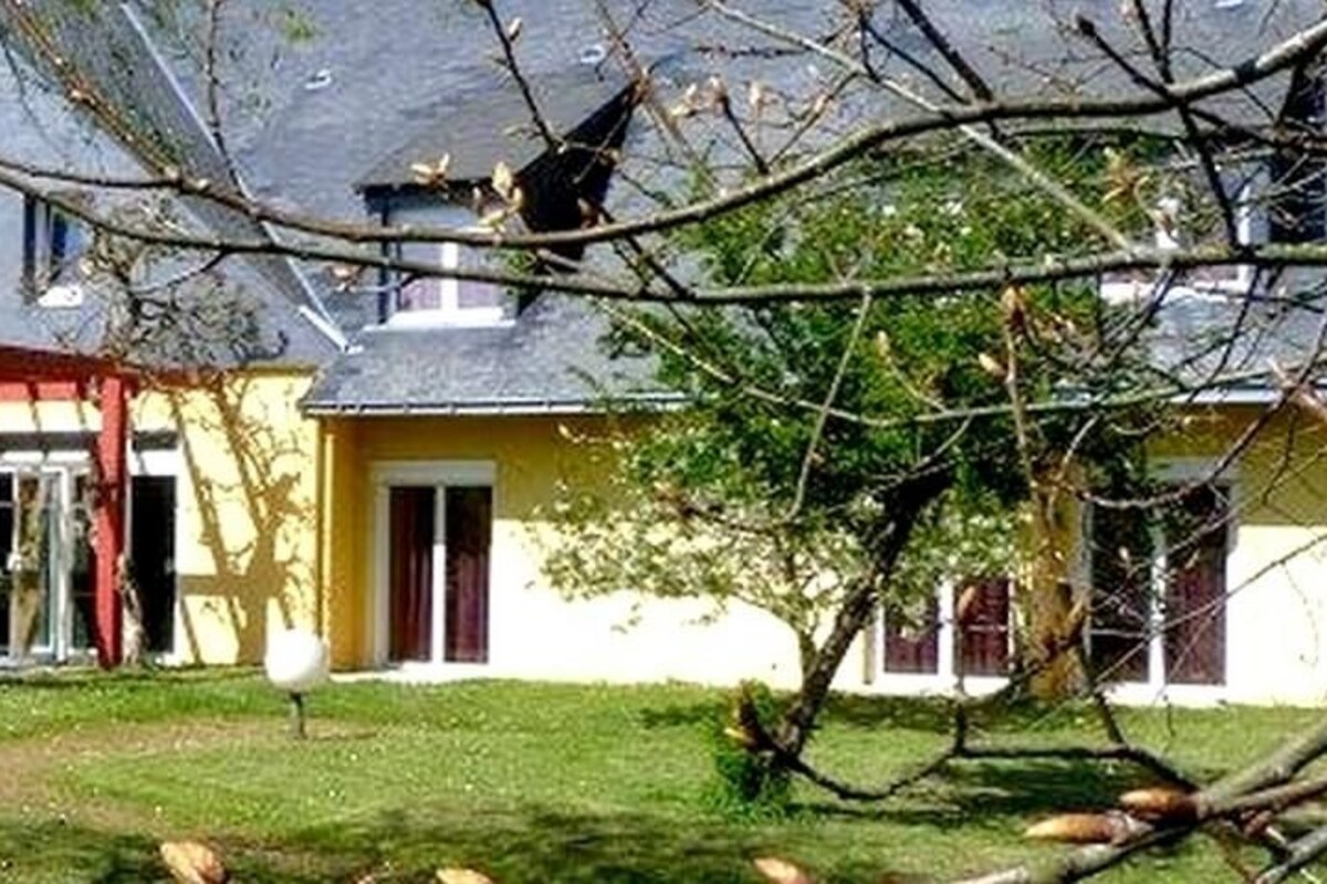 A hotel with a red awning, a covered entrance, and a well-maintained lawn.