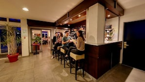 Una zona de bar con asientos, una planta en maceta y una barra con la carta.