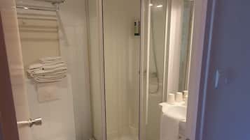 A bathroom with a glass-enclosed shower, a toilet, and a sink.