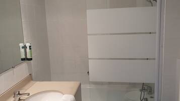 Une salle de bain équipée d’un lavabo, d’un miroir, d’une baignoire et de toilettes.