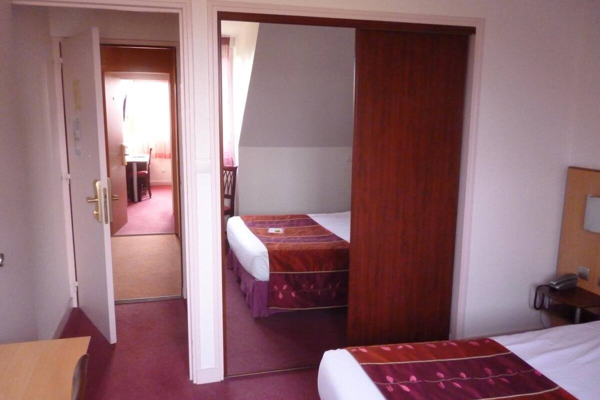Een kamer met twee bedden, een houten garderobe, een bureau en een stoel.