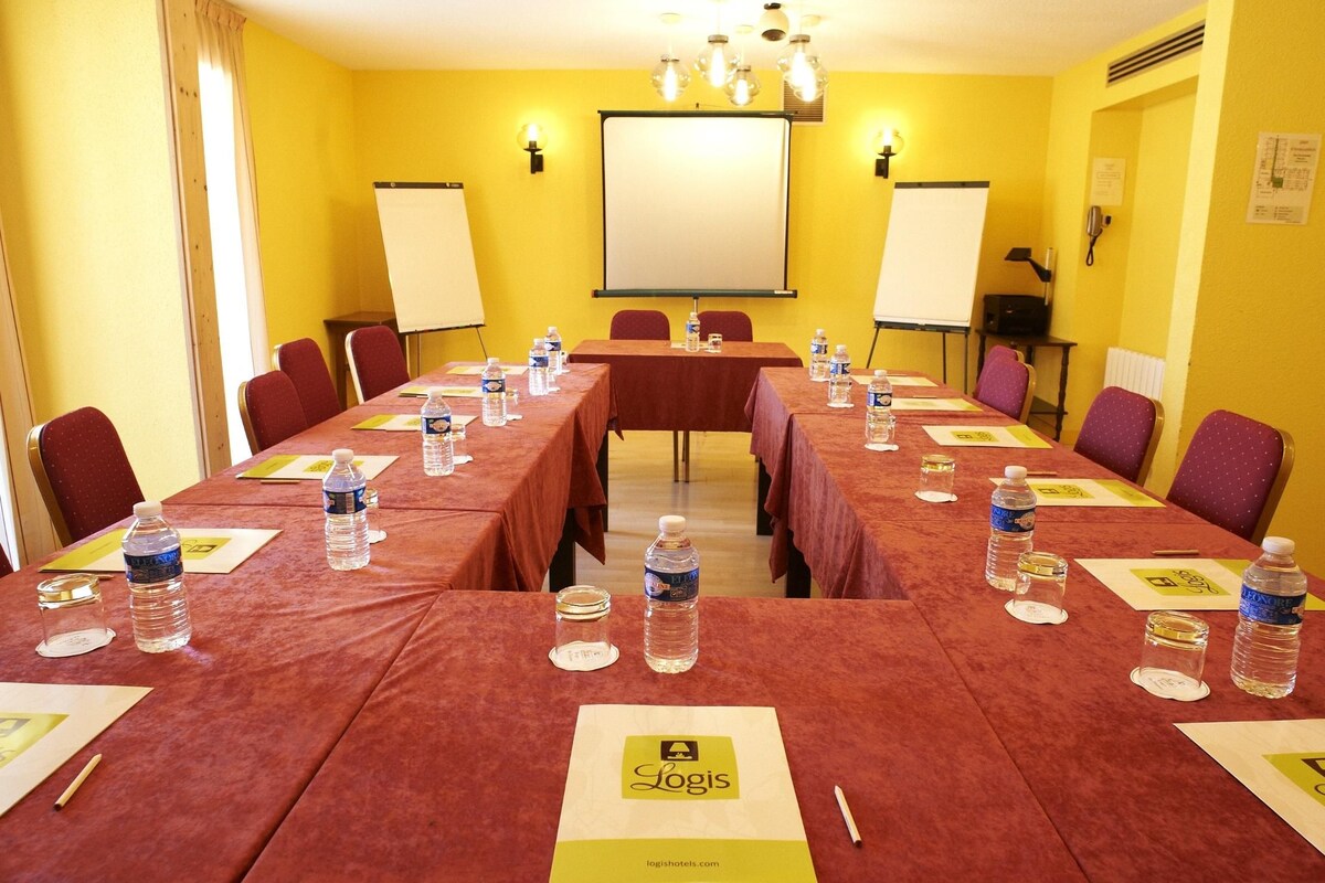 A conference room with a long table, chairs, water bottles, and a whiteboard.