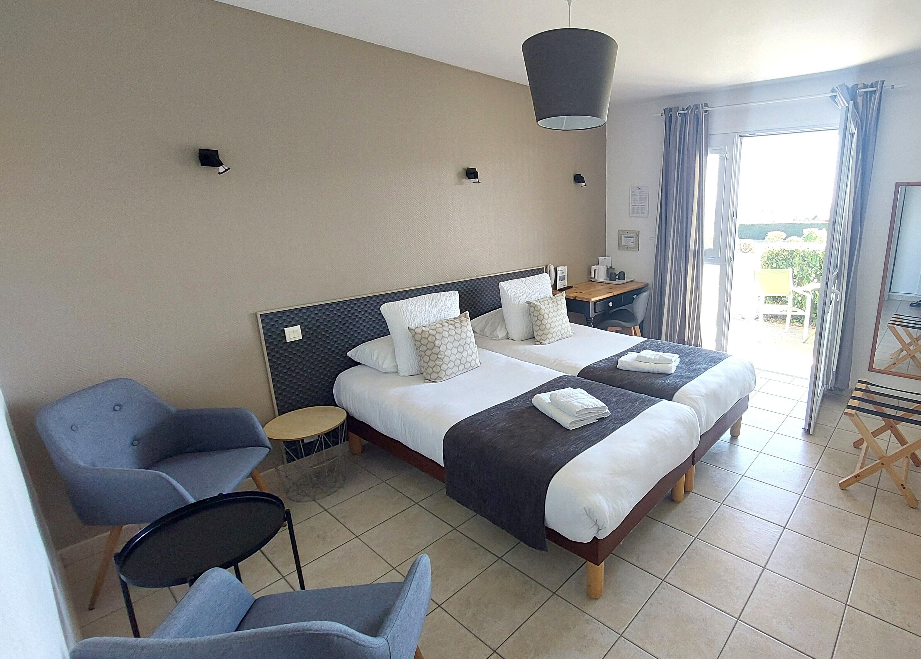 Une chambre d’hôtel avec deux lits, un bureau, une chaise et un balcon.