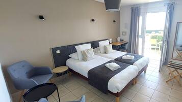 Une chambre d’hôtel avec deux lits, un bureau, une chaise et un balcon.