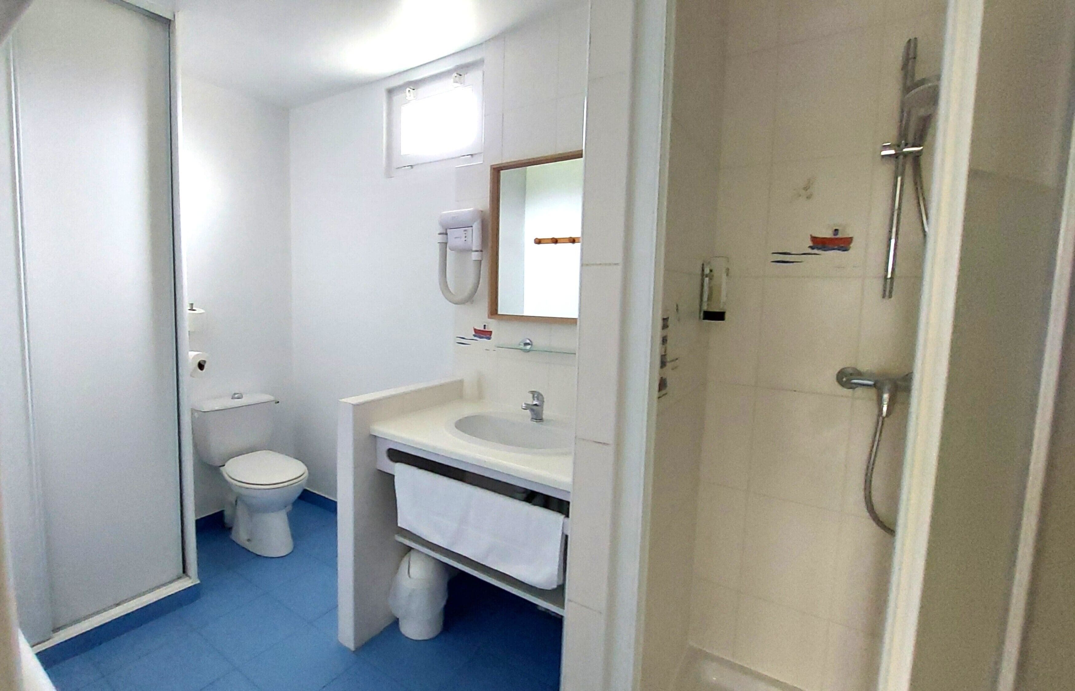 A compact bathroom with a toilet, sink, and shower.