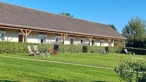 A building with a flat roof, multiple windows, and a covered outdoor area with chairs. - Hôtel La Rosière (Tracy-sur-Mer)