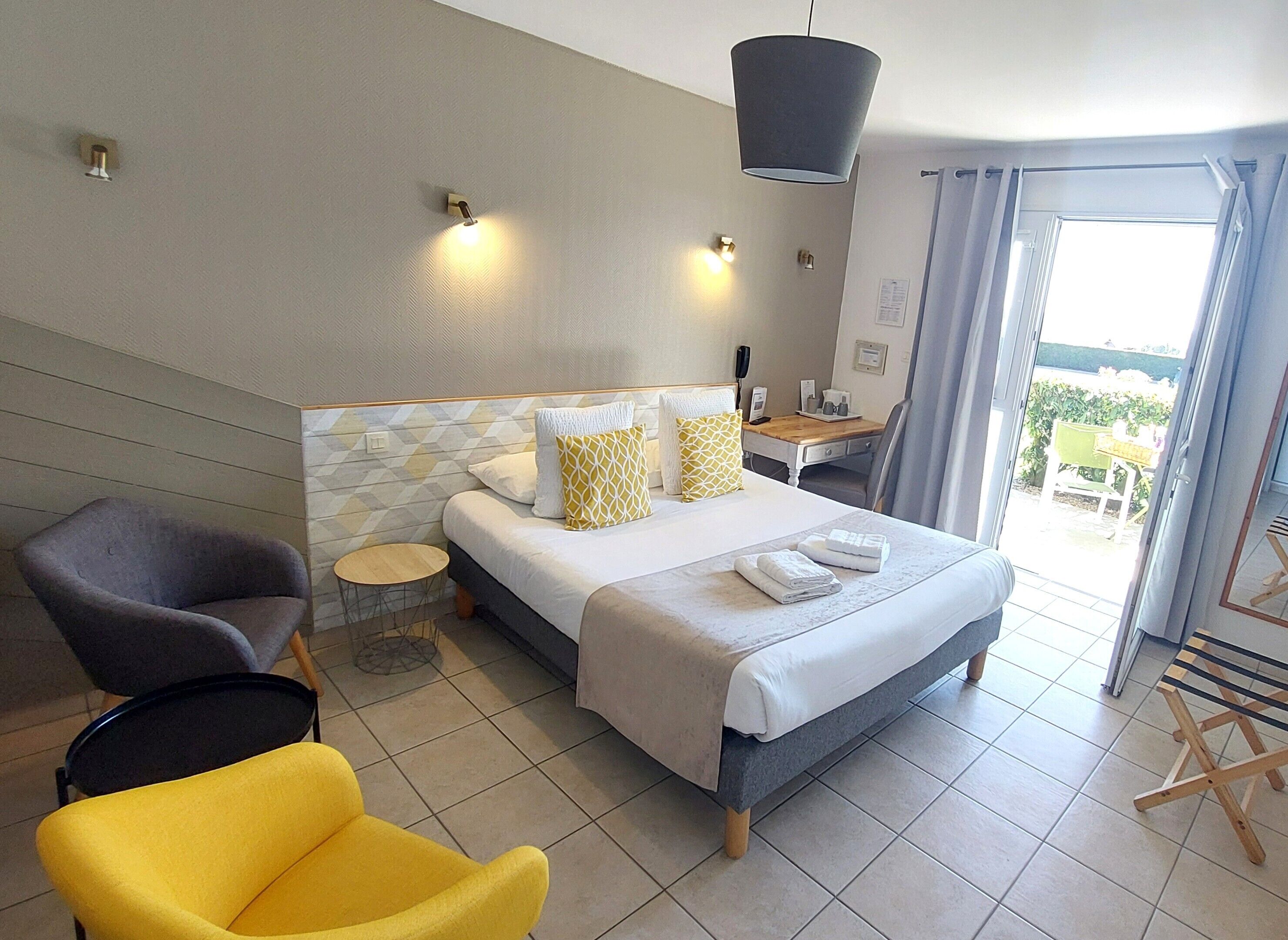 Habitación de hotel con cama, escritorio, silla y vistas al exterior.