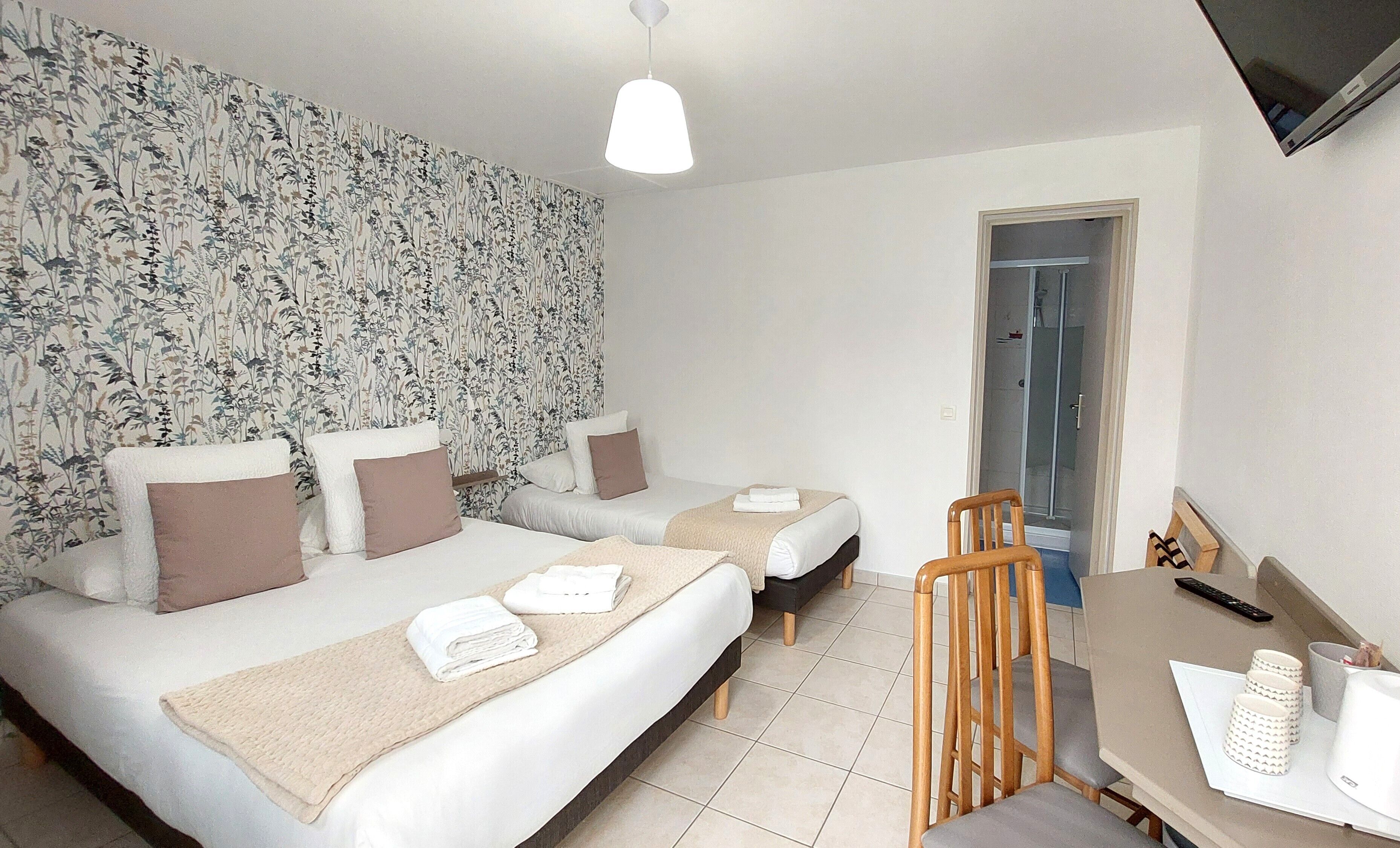 Une chambre d’hôtel avec deux lits, un bureau et un espace douche.