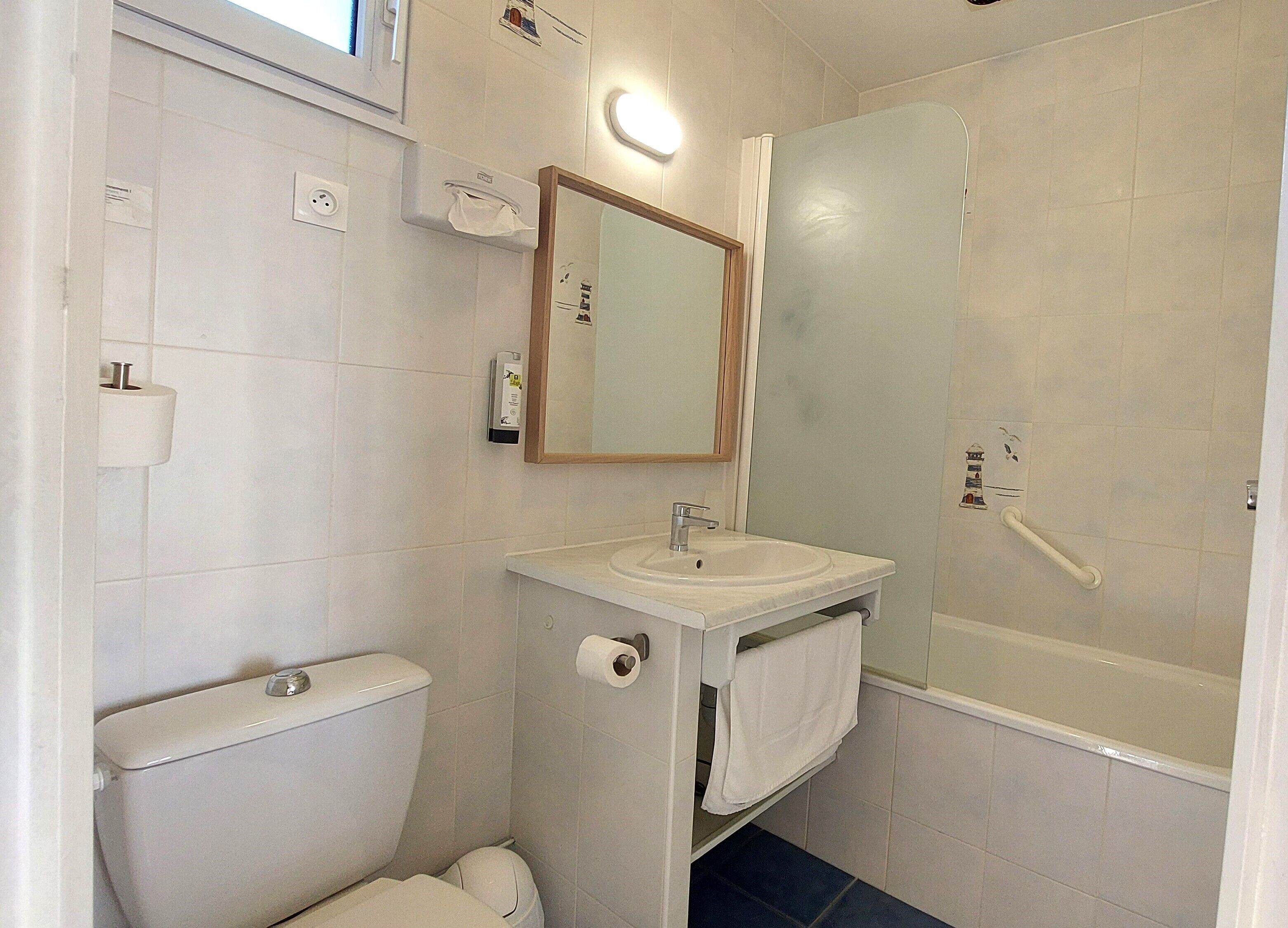 Un baño con inodoro, lavamanos, espejo y ducha.