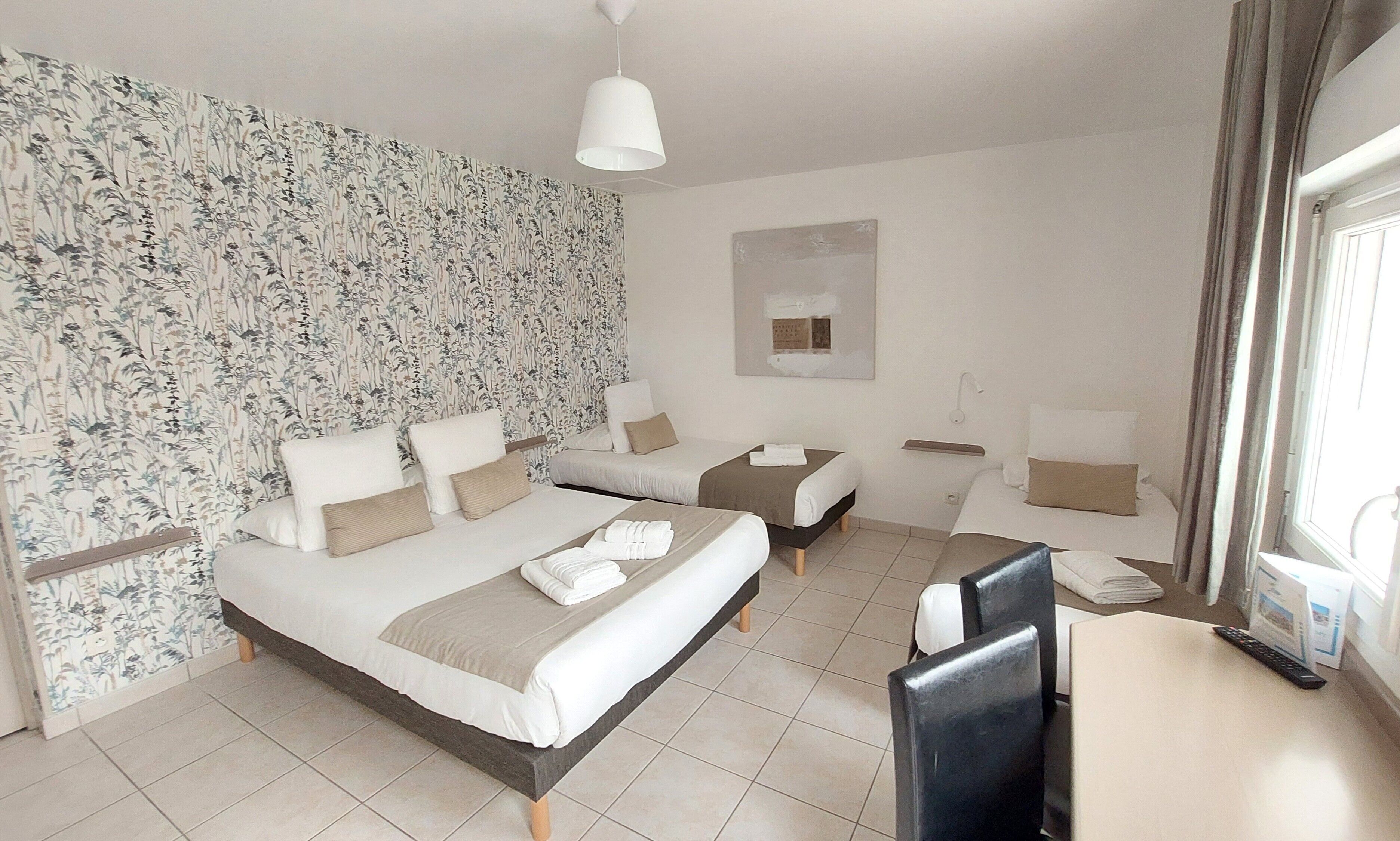 Habitación de hotel con dos camas, un escritorio y una silla.