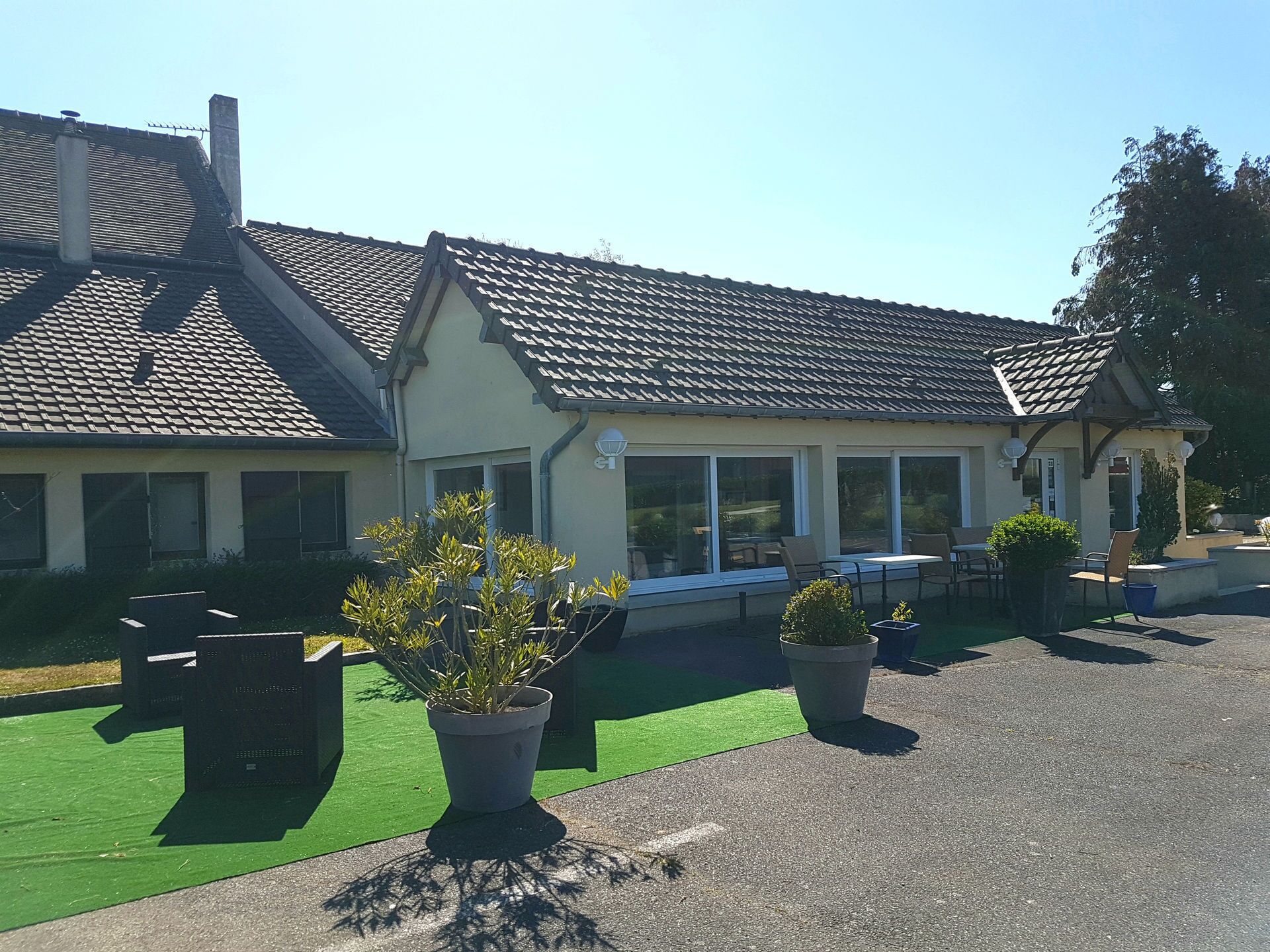 A building with a tiled roof, large windows, and outdoor seating.