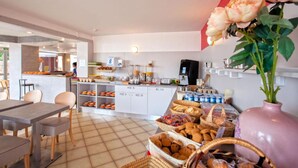 A modern kitchen with white cabinets, a coffee machine, and a variety of food items on the counter. - Hotel Kalliste (Ota)